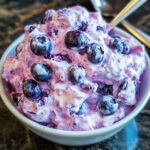 Bowl of creamy blueberry fluff salad with marshmallows and pecans