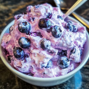 Bowl of creamy blueberry fluff salad with marshmallows and pecans