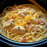 A bowl of Crockpot Cheesy Chicken Spaghetti with melted cheese on top, garnished with parsley.