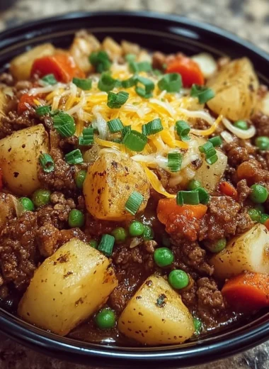 Bowl of creamy hamburger hash with ground beef, potatoes, and peas garnished with herbs